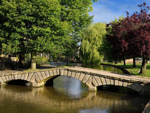a stone bridge over a river in a park at 5 Bed in Lower Slaughter 94643 in Lower Slaughter