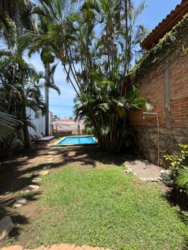 a backyard with a swimming pool and palm trees at Casa Gabriela in Bucerías