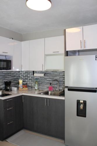 eine Küche mit weißen Schränken und einem Edelstahlkühlschrank in der Unterkunft MV Hideaway - 4 Guests - 5 min airport and beaches - 2 AC in Carolina