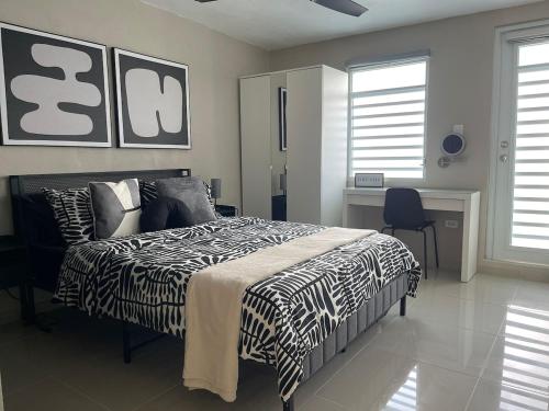 Schlafzimmer mit einem schwarzen und weißen Bett und einem Schreibtisch in der Unterkunft MV Hideaway - 4 Guests - 5 min airport and beaches - 2 AC in Carolina