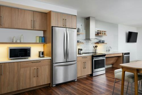 a kitchen with wooden cabinets and a stainless steel refrigerator at Element Knoxville West in Knoxville