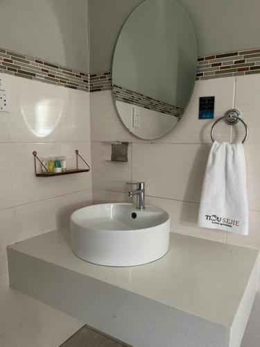 Un lavabo blanco en un baño con espejo. en Tlou- Sejie Hotel, en Palapye
