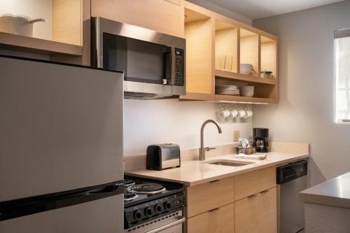 a kitchen with a sink and a stove and cabinets at TownePlace Suites Milpitas Silicon Valley in Milpitas