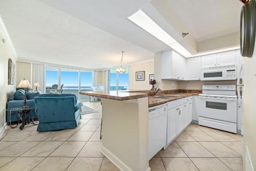 a kitchen with white cabinets and a blue chair at Perdido Sun Unit 914 in Pensacola
