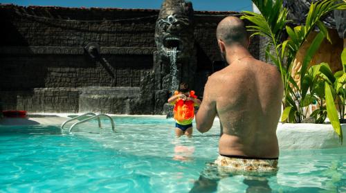 a man and a child in a swimming pool with a fountain at Villa Venecia in Venecia
