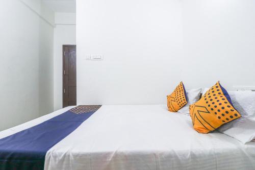 a white bed with three colorful pillows on it at SPOT ON Rohini Inn Kadampuzha in Malappuram