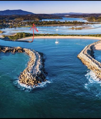a red kite flying over two rocks in the water at The Boathouse a 3 Bedroom House in Narooma