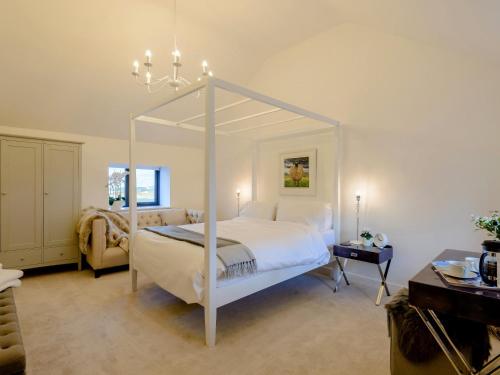 a bedroom with a white canopy bed and a chair at 2 Bed in Cemaes Bay 77640 in Llanfechell