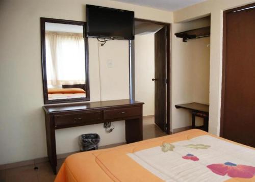 a bedroom with a bed with a dresser and a mirror at Hotel Árbol Grande in Morelia