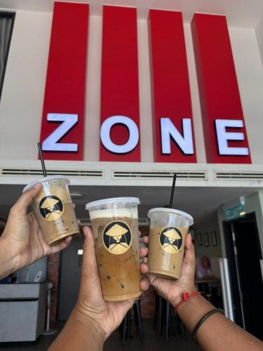 two people holding two cups of coffee in their hands at ZONE Hotels, Eco Grandeur in Bandar Puncak Alam
