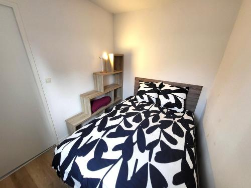 une chambre avec un lit avec une couette noire et blanche dans l'établissement AGREABLE APPARTEMENT REFAIT A NEUF DANS UNE RESIDENCE DE VACANCES - FR-1-92-946, à Les Sables-dʼOlonne
