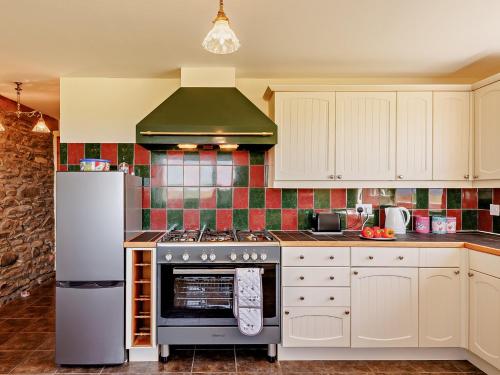 a kitchen with a stove and a refrigerator at 4 Bed in Aberaeron 92072 in Llanrhystyd