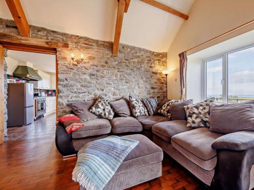 a living room with a couch and a stone wall at 4 Bed in Aberaeron 92072 in Llanrhystyd