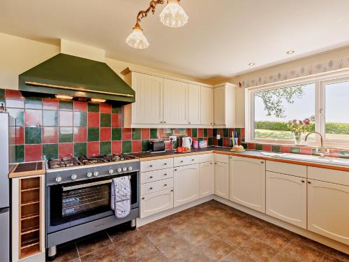 a kitchen with white cabinets and a stove top oven at 4 Bed in Aberaeron 92072 in Llanrhystyd