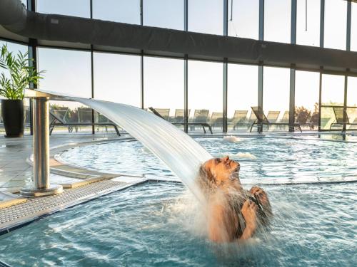 un chien jouant dans une piscine avec un tuyau d'eau dans l'établissement Maison 3 ch, cour privée et Wi-Fi, proche plage et commerces - FR-1-92-949, à Les Sables-dʼOlonne