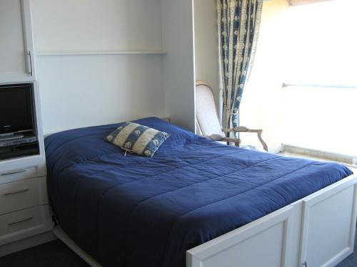 - une petite chambre avec un lit bleu et une fenêtre dans l'établissement Studio face à la mer avec balcon, garage privé et équipements modernes - Les Sables-d'Olonne - FR-1-92-624, à Les Sables-dʼOlonne