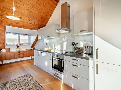 a kitchen with white cabinets and a wooden ceiling at 2 Bed in Haverigg 94052 in Haverigg