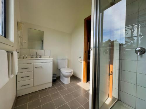 a bathroom with a toilet and a glass shower at Prom Coast Holiday Lodge in Waratah Bay
