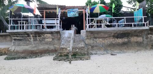 a stand with umbrellas on the beach next to a building at JRM Place in Oslob