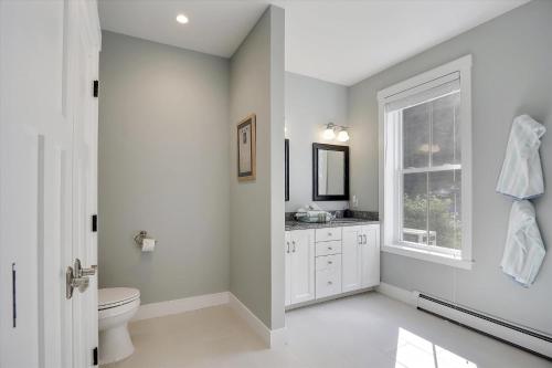 a white bathroom with a toilet and a window at Scharkie Ski Haus in Stowe