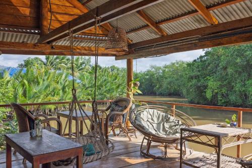 a porch with tables and chairs and a view of a river at Kampot Cabana in Kampot