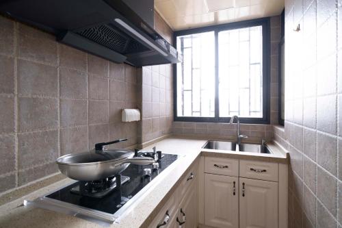 a kitchen with a sink and a bowl on a stove at Book and Bed-Yuyuan 2 in Shanghai