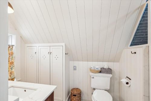a white bathroom with a toilet and a sink at The Cozy Villager in Stowe