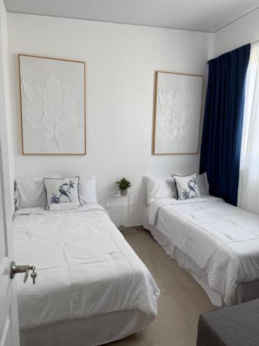 two beds in a room with blue curtains at Elegante casa a minutos de Centro comercial in San Miguel