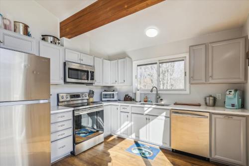 a kitchen with white cabinets and stainless steel appliances at Mountainview Condo #2 in Stowe