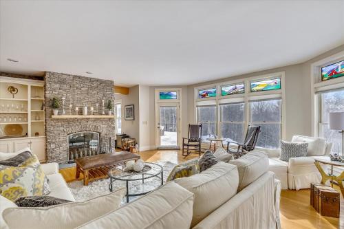 a living room with white furniture and a brick fireplace at The Eagle's Nest at Stowe in Stowe