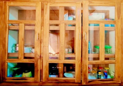 a wooden cabinet with glass doors with dishes in it at Mango garden villa in Pottuvil