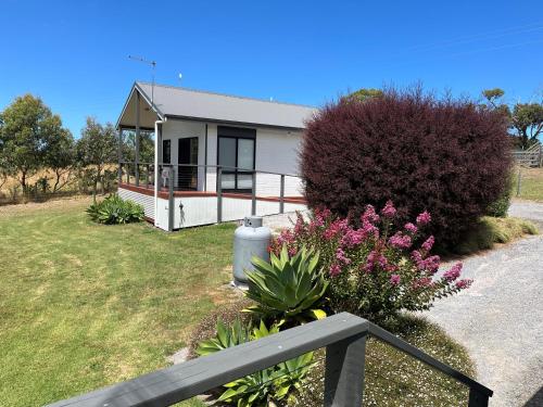 a small white house with a fence and flowers at Prom Coast Holiday Lodge in Waratah Bay