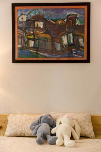 two stuffed animals sitting on a couch under a painting at Lúa homestay in Hue