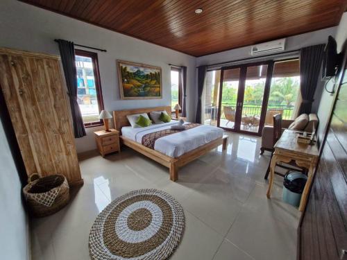 une chambre avec un lit, une table et des fenêtres dans l'établissement Merta Ubud Homestay, à Ubud