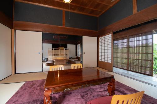 a dining room with a wooden table and some windows at Kamakurayama Farm - B&B Satoyama in Uda