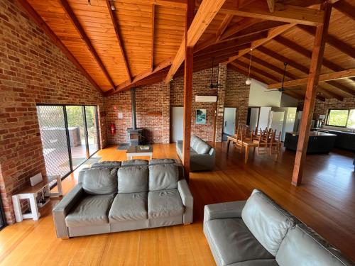 a living room with leather furniture and a brick wall at Prom Coast Holiday Lodge in Waratah Bay