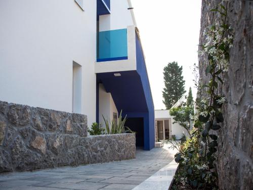 a blue and white house with a stone wall at Apartments Petra in Njivice
