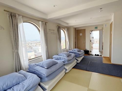 four beds in a room with large windows at オレンジの風 in Imabari