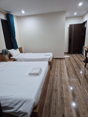 a hotel room with two beds and a wooden floor at Hoang Kim Hotel in Vientiane