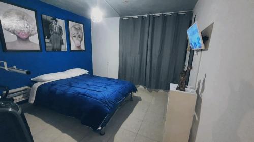 a blue bedroom with a bed and a television at Casitas in Mexico City