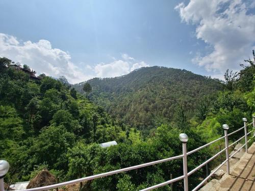 a view of a mountain with trees and a railing at ANURAA by Casa De Bello, Kainchi Dham in Bhowāli