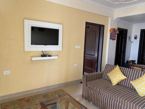a living room with a couch and a tv on the wall at The Alpine Ramgarh in Rāmgarh
