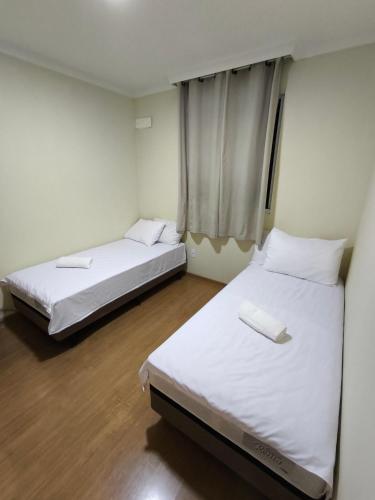 two beds in a room with white walls and wooden floors at Apartamento em Salvador in Salvador
