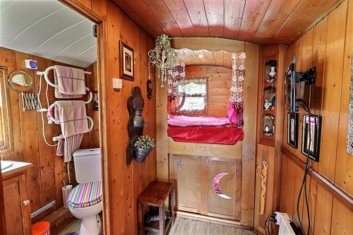 a cabin with a toilet and a bed in it at Roulotte la comtesse gitane in Plescop