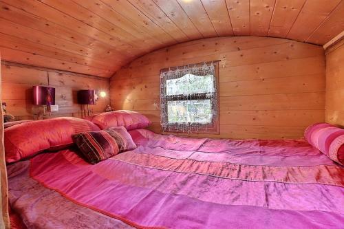 a large pink bed in a room with a window at Roulotte la comtesse gitane in Plescop