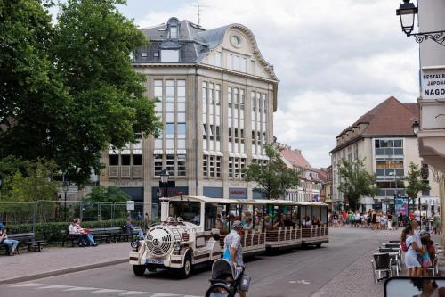an old trolley car driving down a city street at Le 7 KLÉBER in Colmar
