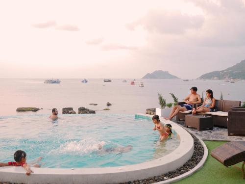 a group of people in a swimming pool next to the water at DD Hut Koh Tao in Koh Tao