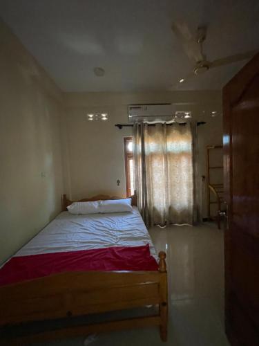 Un dormitorio con una cama y una ventana con cortinas. en Kumar inn, en Jaffna