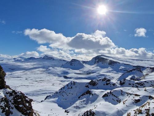 a snow covered mountain with the sun in the sky at Wavecrest in Staffin