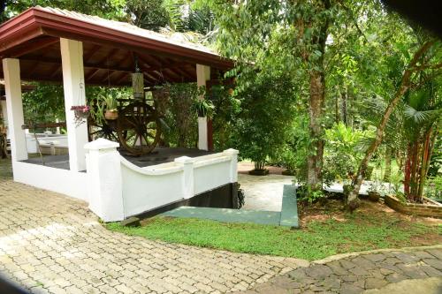 a gazebo with a cannon in a garden at Mango Breeze Hikkaduwa in Gonapinuwala West